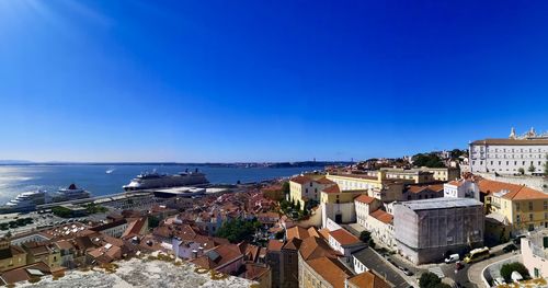 High angle view of townscape by sea against clear blue sky