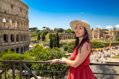 Portrait of young woman standing against building