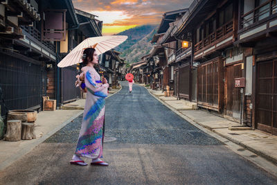 Rear view of woman with umbrella walking on street