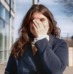 Woman touching her face while standing outdoors