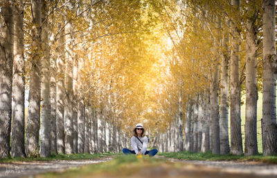 Woman sitting amidst autumn trees at park