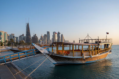 Ship moored in sea against buildings in city against clear sky