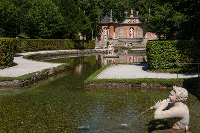 Built structure by lake against trees and plants in garden