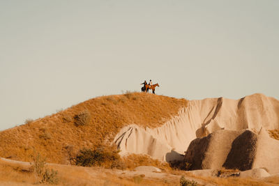 People on desert against clear sky