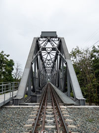 The perspective view of the steel railway bridge is crossing the large river.