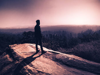 Silhouette man standing on mountain against sky during sunset