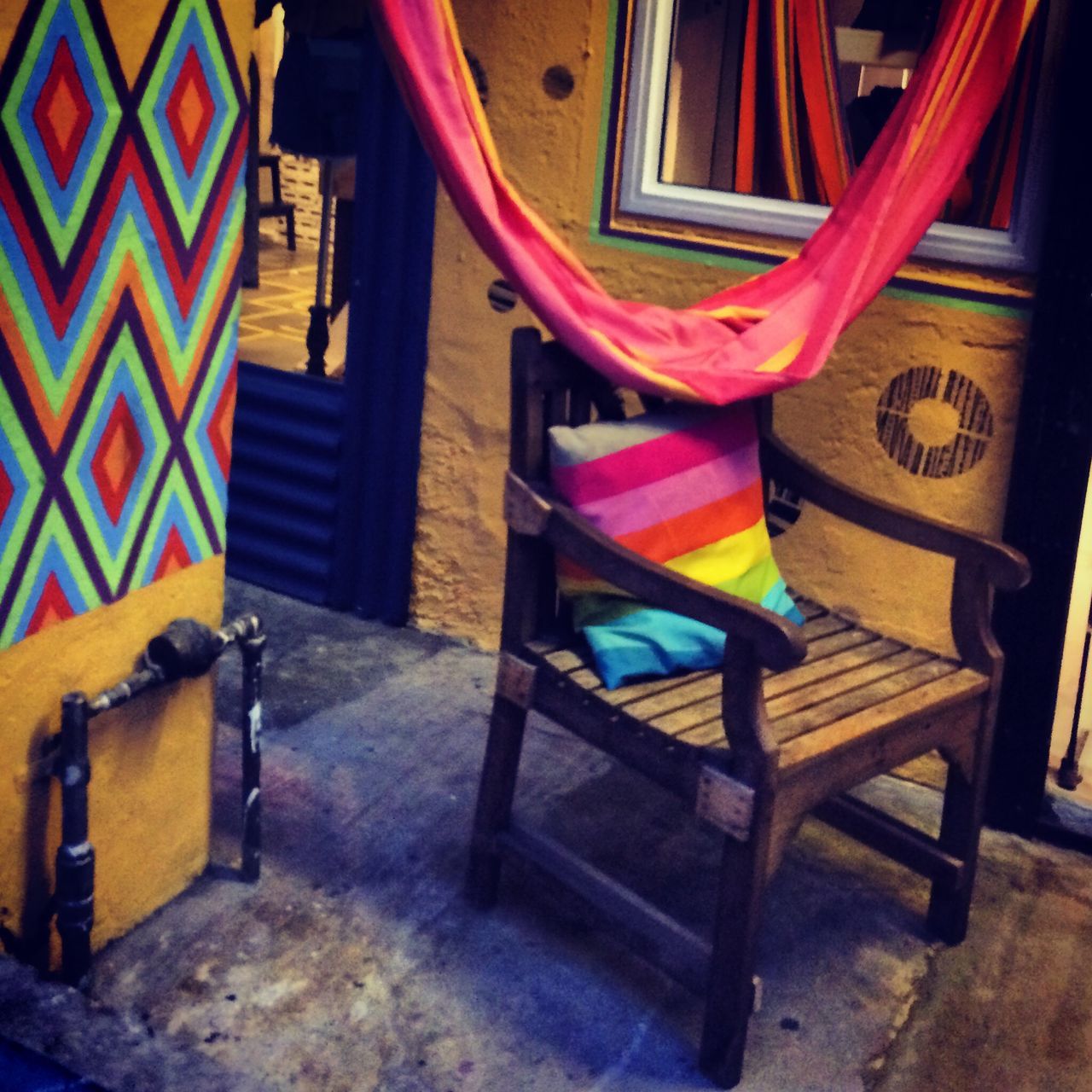 chair, indoors, absence, table, built structure, wood - material, empty, architecture, no people, furniture, hanging, wall - building feature, day, multi colored, sunlight, seat, potted plant, house, text, building exterior