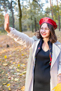 Portrait of smiling young woman standing against trees