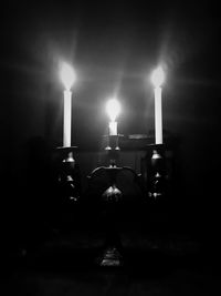 Man holding illuminated candles against dark wall