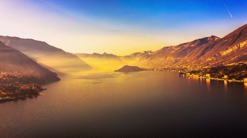 Scenic view of lake and mountains against sky during sunset