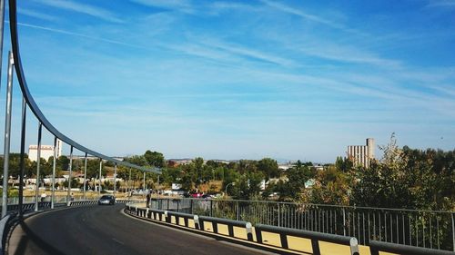 Bridge over road against blue sky in city