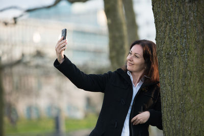 Businesswoman taking selfie through mobile phone at park