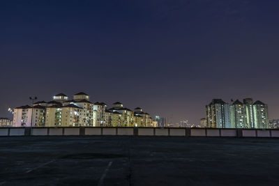 Illuminated city buildings against clear sky at night