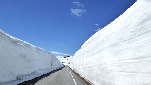 Empty road amidst snow covered walls