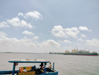 People on boat in sea against sky