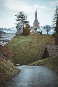 Scenic view of building by trees against sky