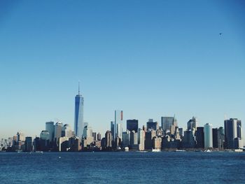 Sea by modern buildings against clear sky