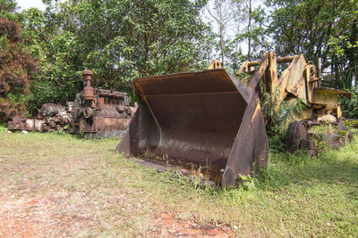 Old abandoned building by trees on field