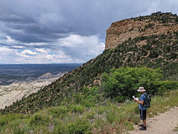 Rear view of man walking on mountain against sky