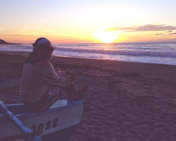 Man looking at sea against sky during sunset