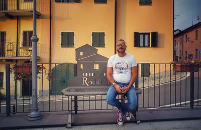 Portrait of man sitting against building in city