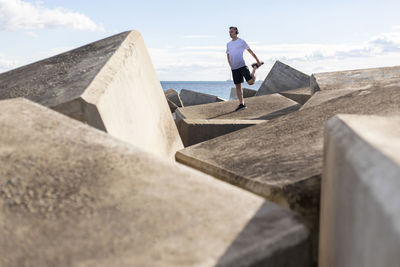 Man stretching legs on rocks near sea