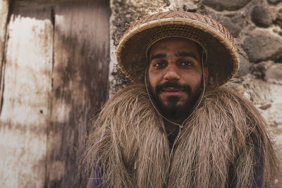 Portrait of man wearing traditional straw wig against wall