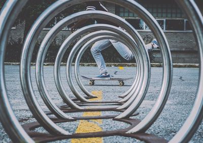 Low section of person skateboarding by bicycle rack