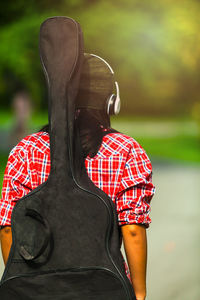 Rear view of woman carrying guitar at park