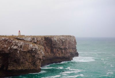 Rock formations by sea against clear sky