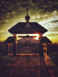 Gazebo by building against sky during sunset