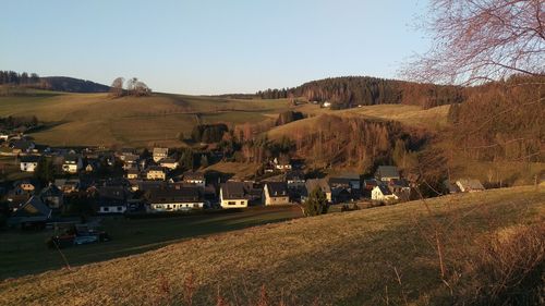 Scenic view of field by houses against sky