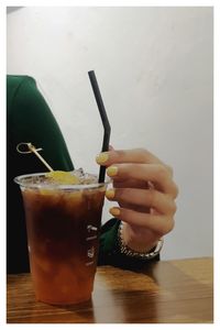 Close-up of hand holding drink on table