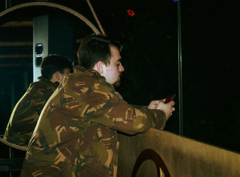 Side view of young man standing in window