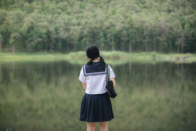 Rear view of woman standing by lake