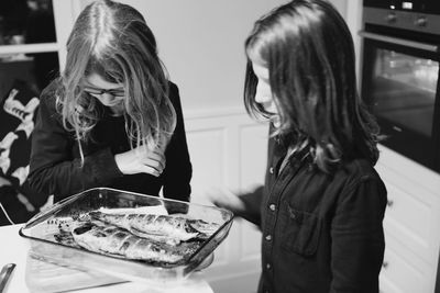 Girls standing by fish in tray at table
