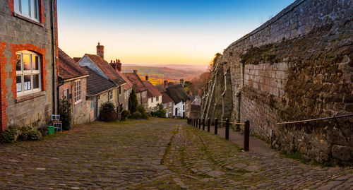 Street amidst buildings in town during sunset