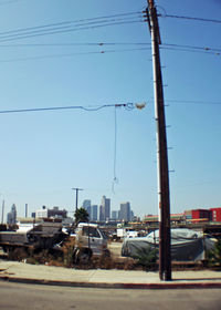 Electricity pylon by city against clear sky