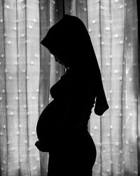 Side view of silhouette woman standing against window