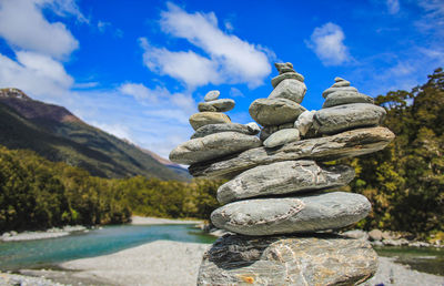 Stack of stones by rocks against sky