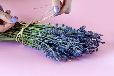 Woman with purple manicure arranging lavender bouquet, closeup