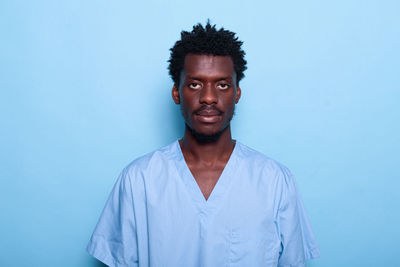 Portrait of young man standing against blue background