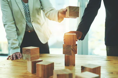 Midsection of businessman playing with toy blocks