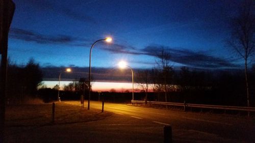 Illuminated road against sky at night