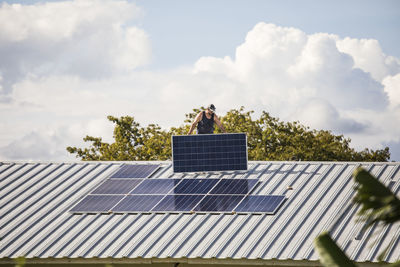 Electrician carries solar panel on rooftop.