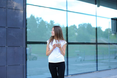 Young businesswoman standing by glass window in office