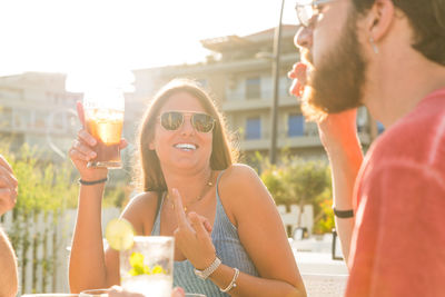 Young woman drinking water from glass while sitting outdoors