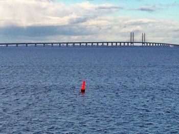 Bridge over sea against cloudy sky