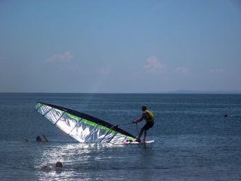 People in sea against sky