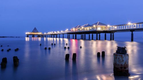 Illuminated bridge over river against sky at night